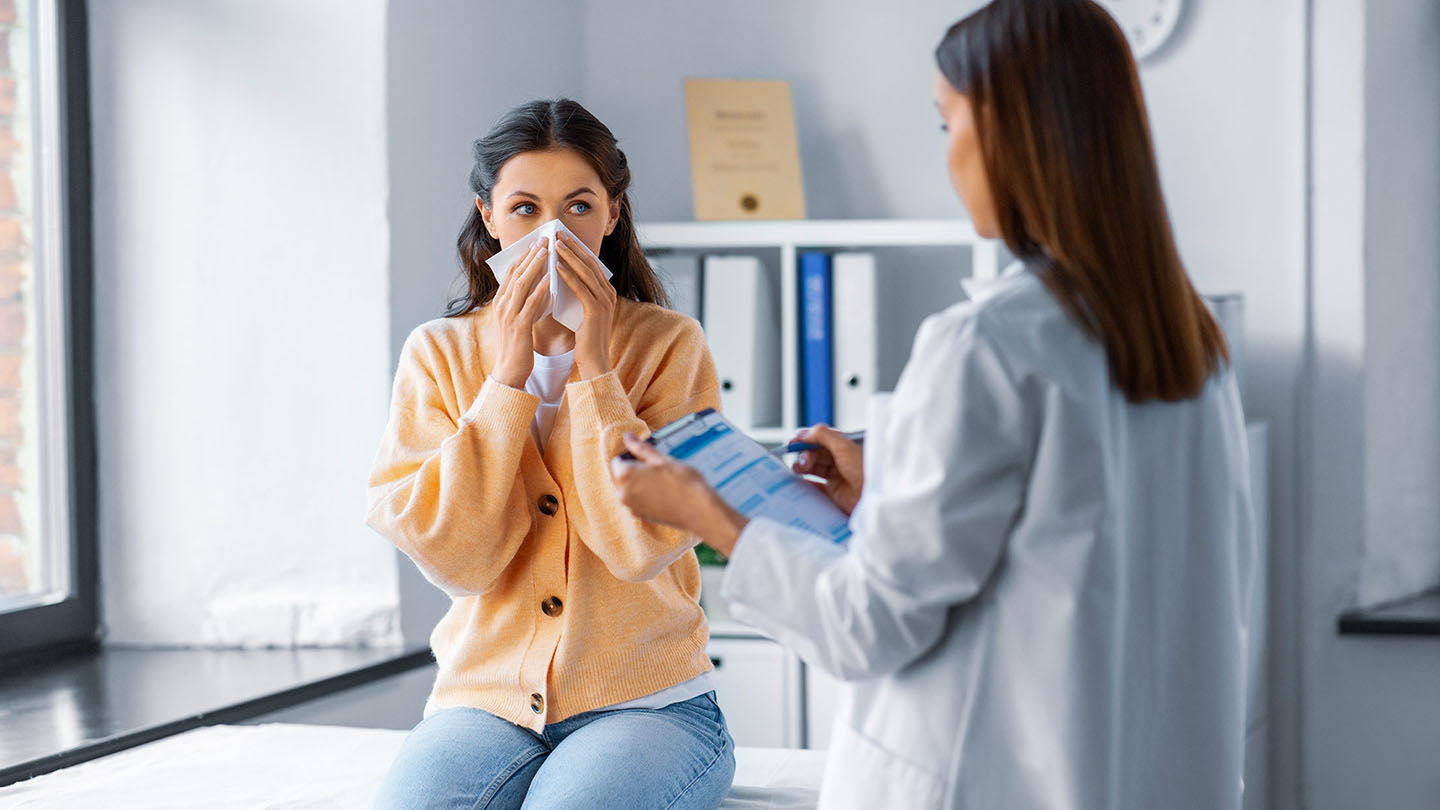 Žena s gripom koju pregledava liječnik.