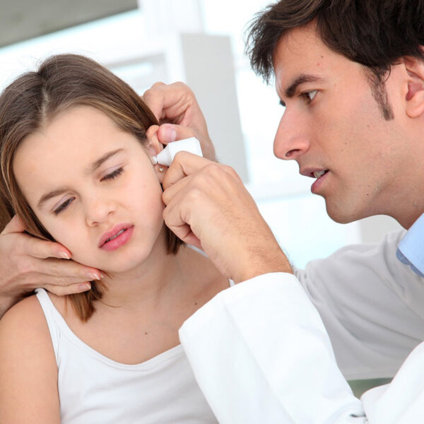 Djevojčica koju pregledava liječnik zbog upale uha.