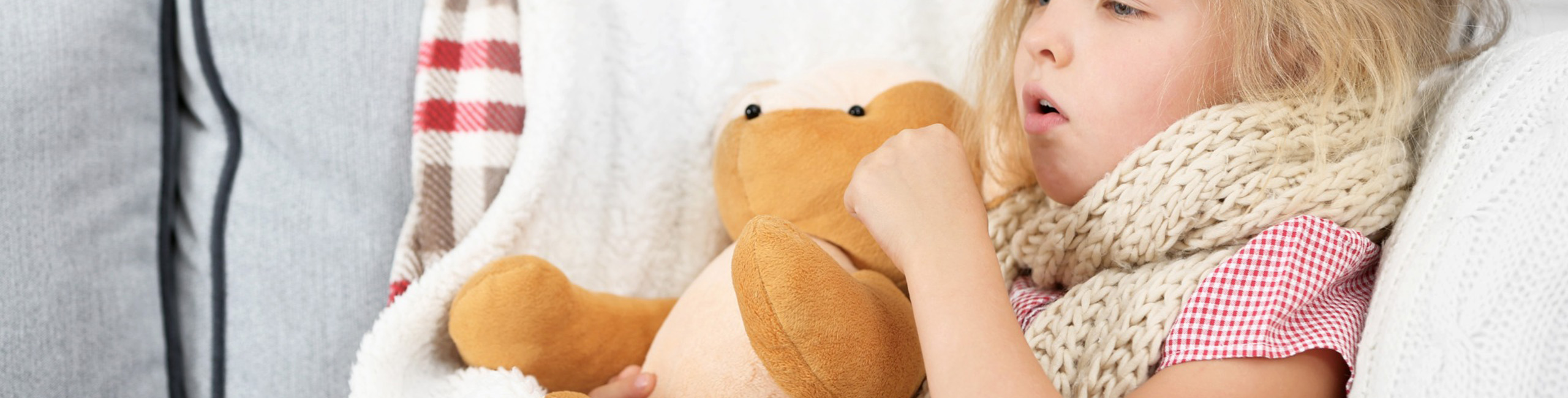 Bolesna djevojčica čvrsto se drži plišane igračke.