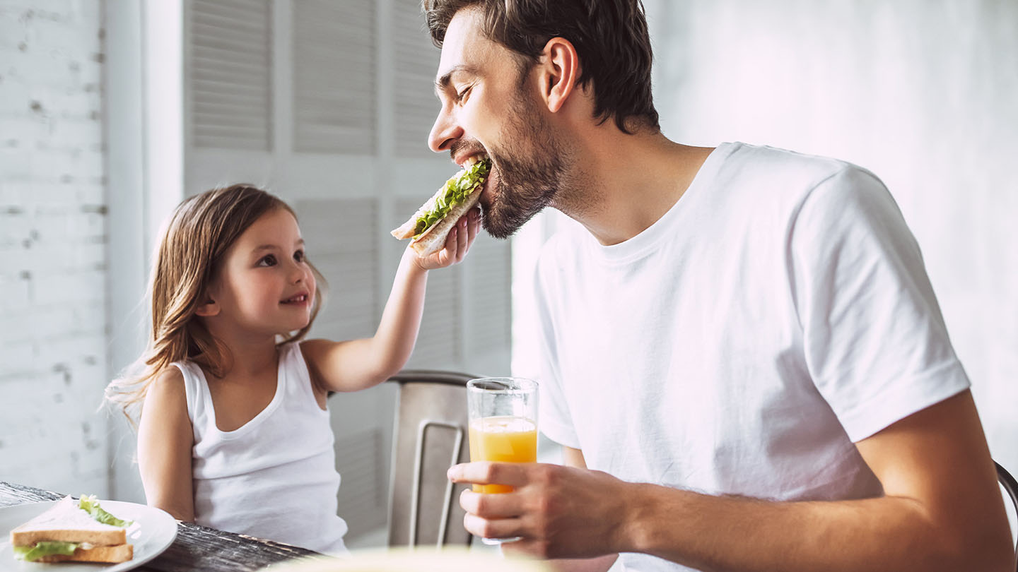 Otac i dijete uživaju u sendviču.