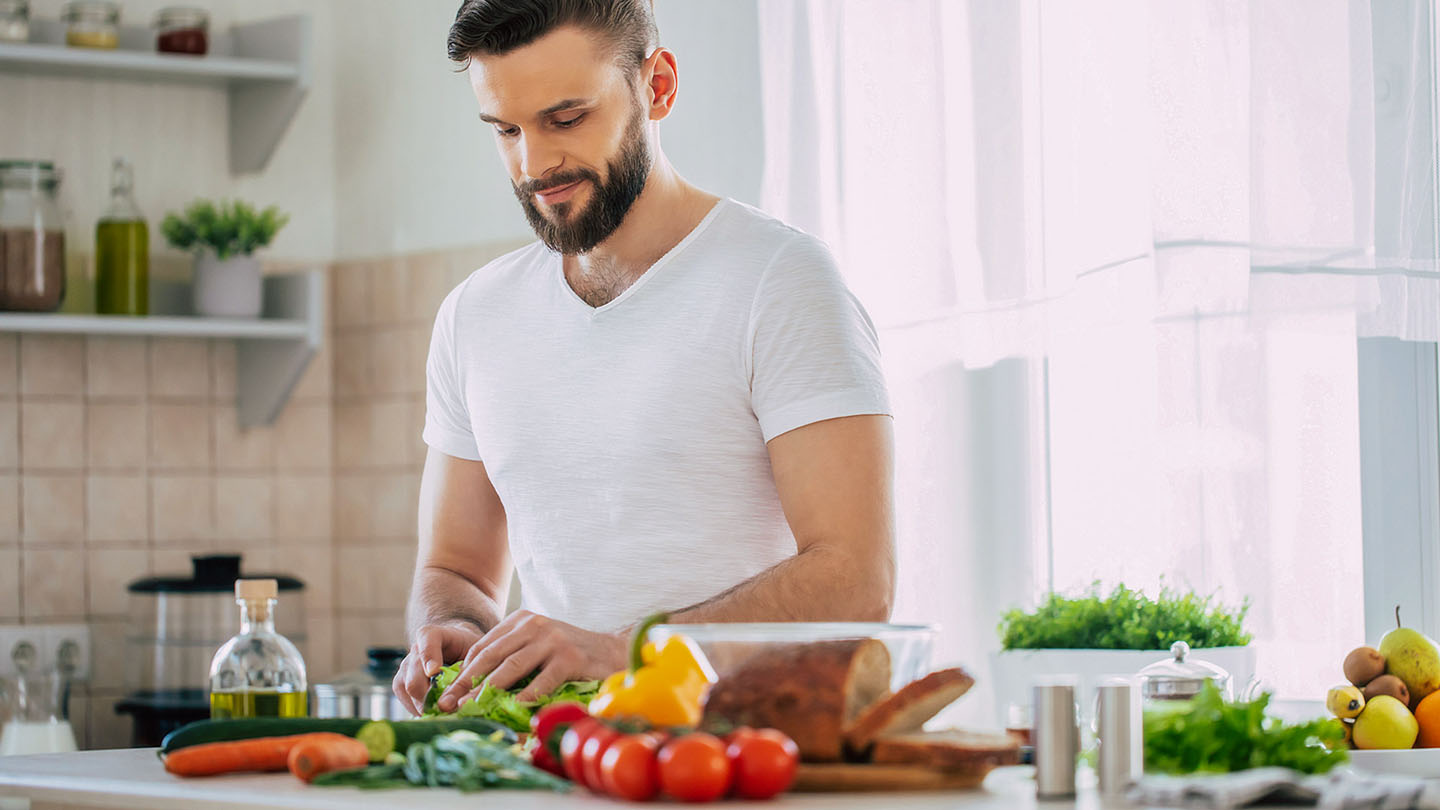 Muški sportaš priprema zdrav obrok u kuhinji.