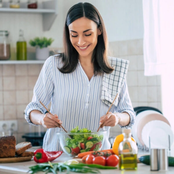 Žena priprema zdravu salatu punu vitamina C i cinka.